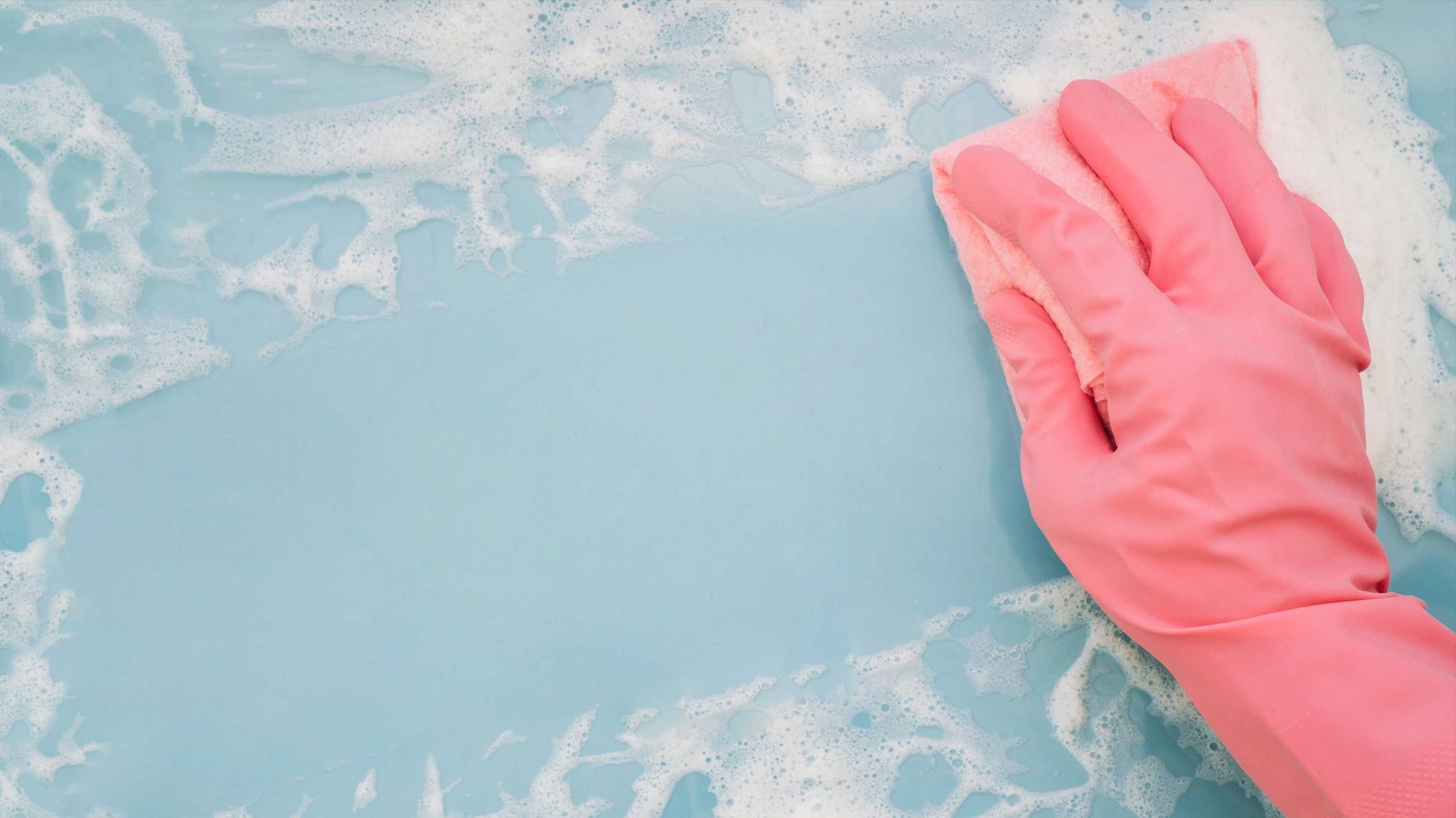 Mano con guante limpiando una superficie con espuma
